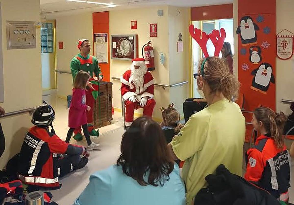 Los niños saludan a Papá Noel, el elfo mago y los bomberos a su llegada a la planta de Pediatría.