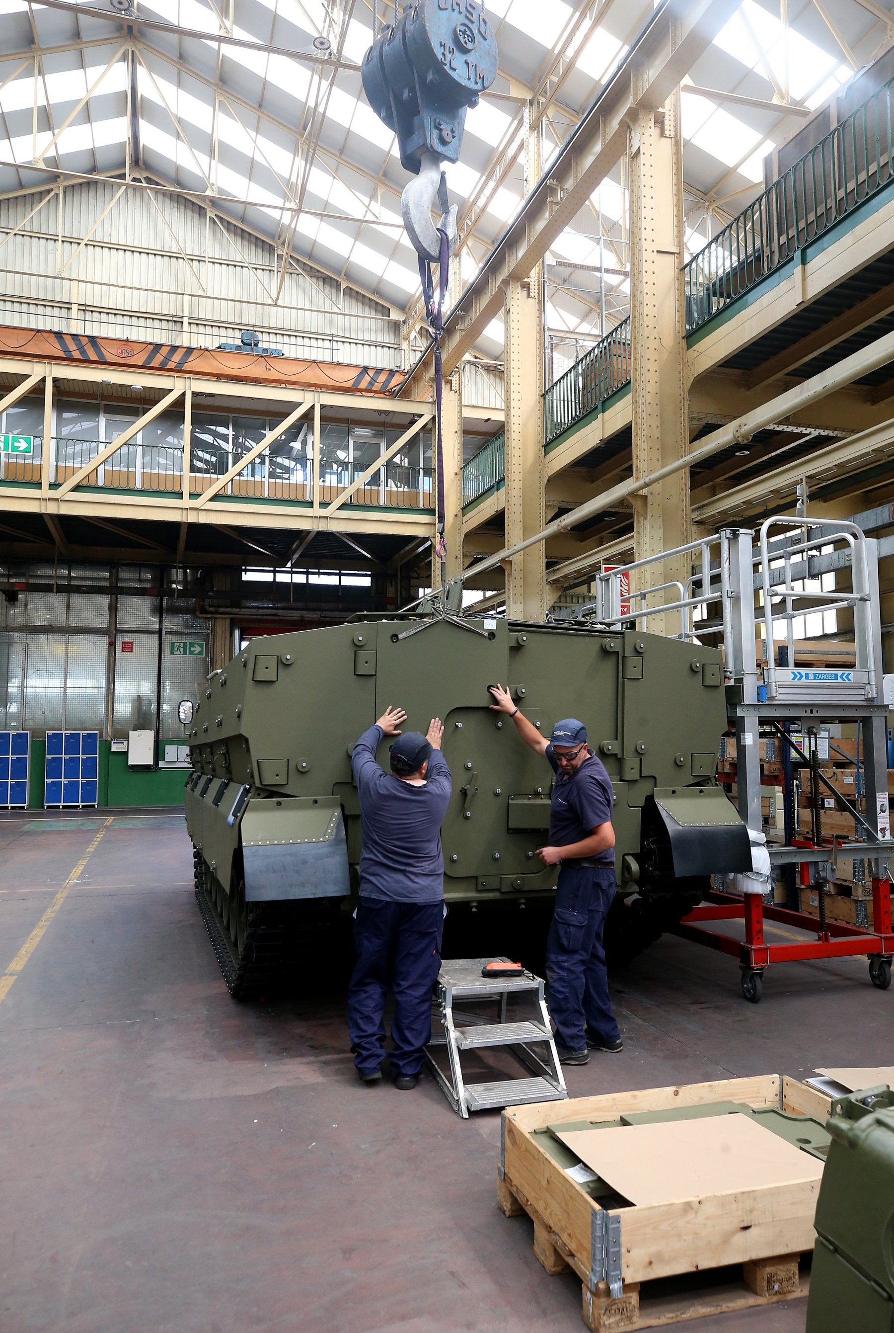 Operarios de la fábrica de armas de Trubia, con un blindado.