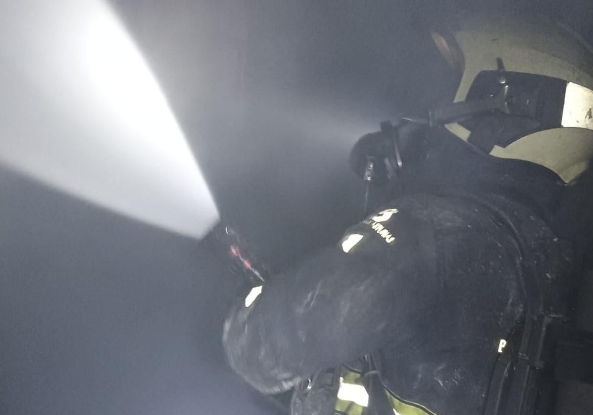 Un bombero sofoca las llamas en el interior de la vivienda.