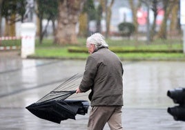 Un hombre, con el paraguas destrozado por el viento durante uno de los últimos temporales en Asturias.