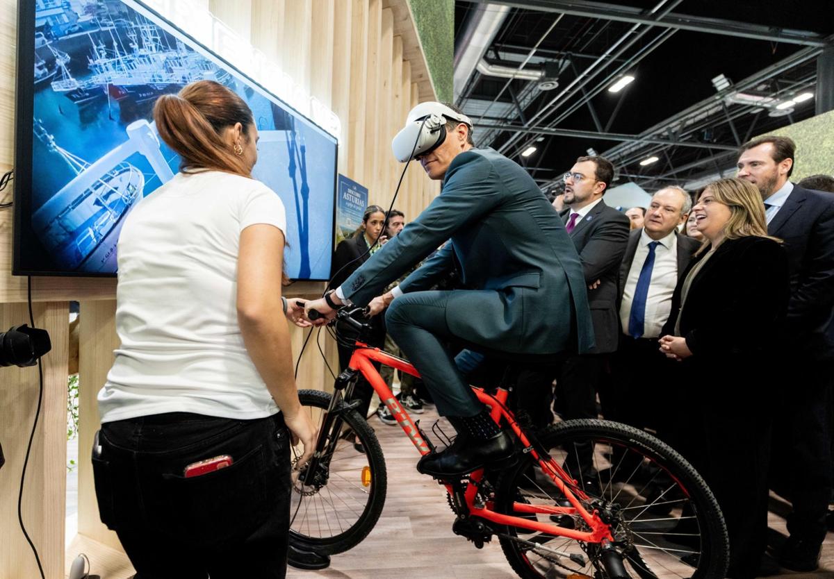 Pedro Sánchez prueba la bici con realidad virtual instalada en el estand de Asturias en Fitur.