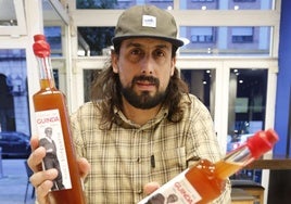 Borja Alcázar enseña dos botellas de su licor de guinda.