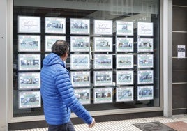 Un hombre consulta los anuncios de una inmobiliaria en Avilés.