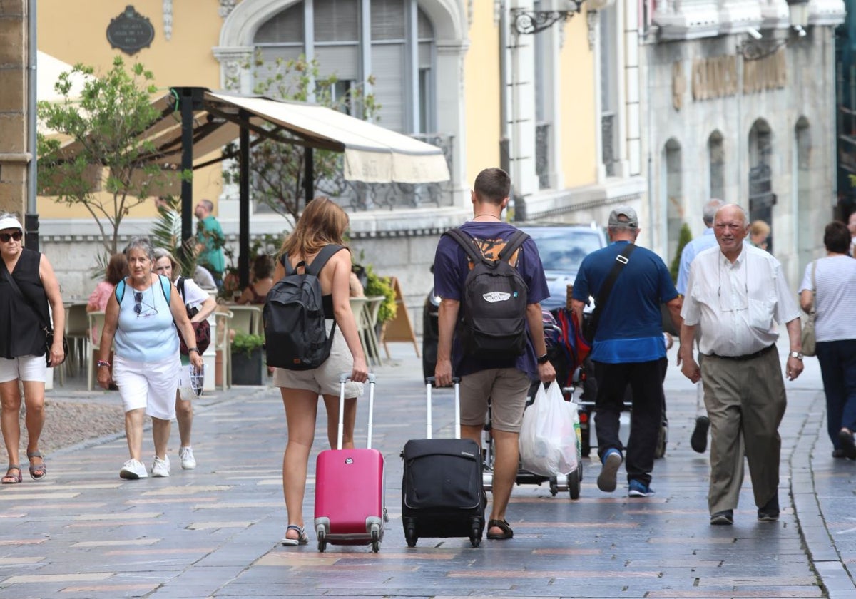 Dos turistas pasean con sus maletas por el centro de Avilés.