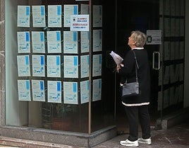 Una mujer consulta las ofertas de alquiler y compra de viviendas de una inmobiliaria de Avilés.