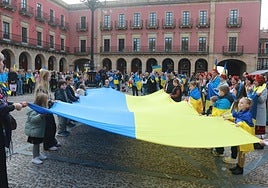 Niños ucranianos sujetan una bandera de grandes dimensiones durante la manifestación en apoyo de Ucrania.