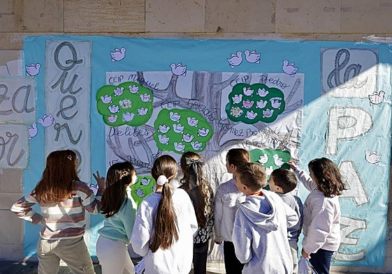 Unos niños realizan un mural de la paz en el patio del colegio.