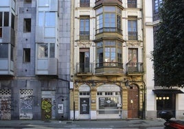 Portal de madera donde llegaron a colarse los okupas. A la izda, edificio desalojado hace un año.