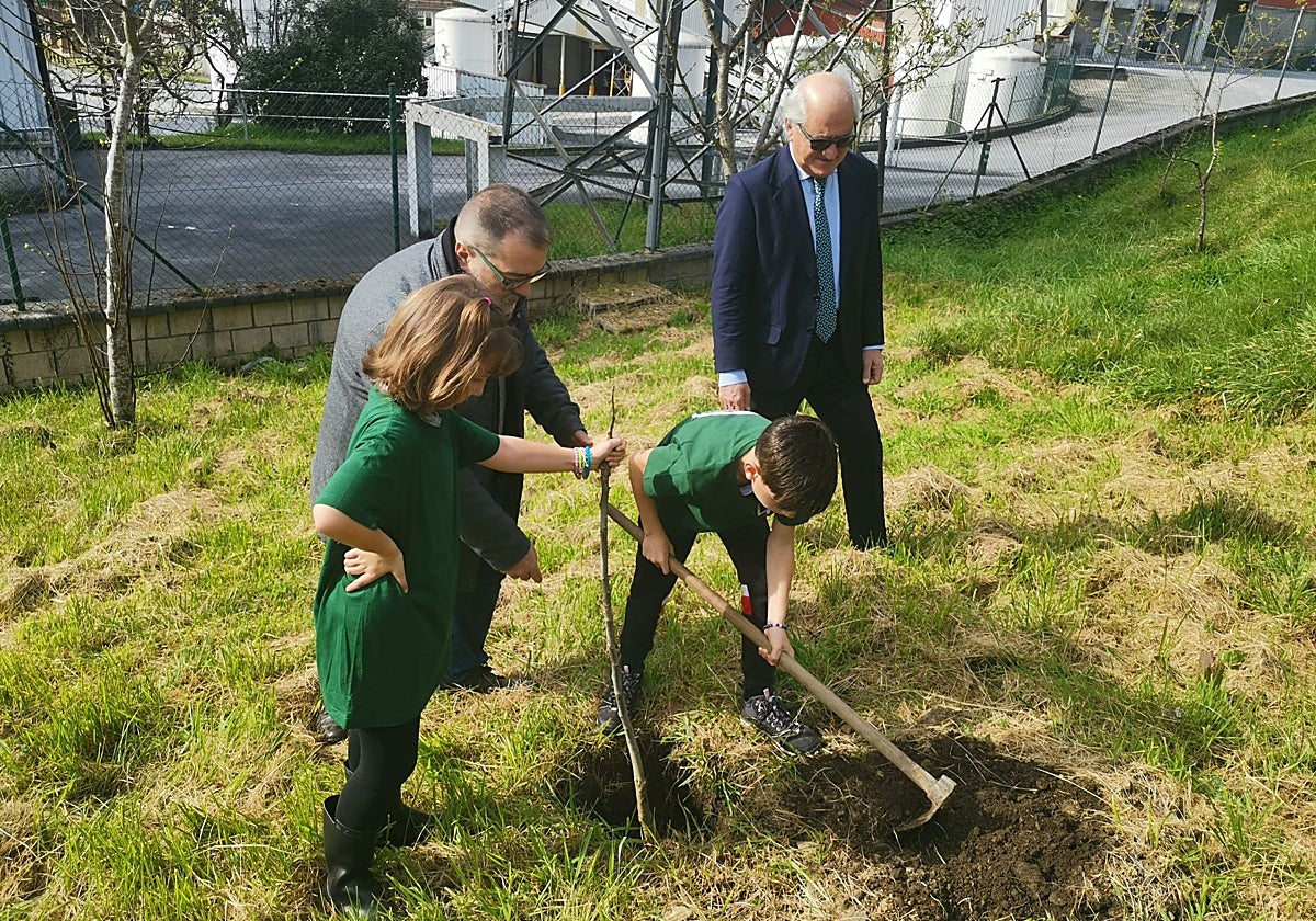 El alcalde de Langreo, Roberto García, ayuda a los pequeños Carla Marcial y Bruno Suárez a plantar un árbol frutal junto a las instalaciones de la Corporación Masaveu, en Riaño. Les acompaña José Luis Saenz de Santamaría, director de Relaciones Institucionales de la empresa