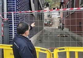 Lalo Fernández señala su casa al otro lado de la valla que cierra la zona de la explosión, en el barrio de La Villa, Mieres.