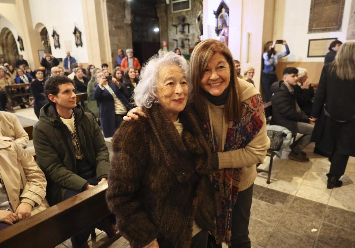 María Teresa Álvarez, pregonera de la Semana Santa de Avilés 2025, abraza a la autora del cartel, Severita Menéndez, en el acto de presentación.