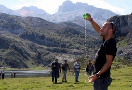 Un turista escancia un culín de sidra ante el lago Ercina, en los Picos de Europa.