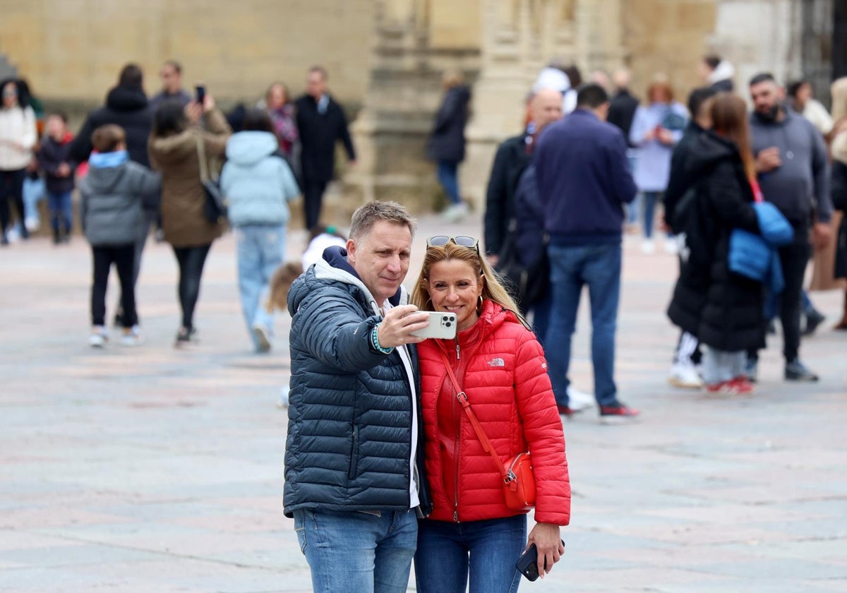 Una pareja se hace una foto ante la catedral de Oviedo.
