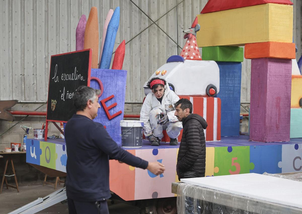 Imagen secundaria 1 - A la izquierda, Esther Cuesta conversa con sus compañeros sobre el trabajo de la carroza. A la derecha, hacen un repaso a la maqueta para que la carroza sea lo más igual posible.