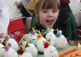 Una niña admira güevos pintos expuestos en el mercado de Siero.