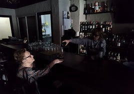 La dueña de La Botelluka, sirviendo a oscuras una copa de vino en su local de Gijón.