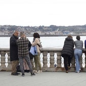 Varias personas miran hacia la playa en el paseo del Muro, en Gijón.
