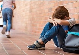 Un pequeño llora, solo, sentado en el suelo del colegio.