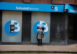 Una mujer retira dinero de un cajero de Banco Sabadell Herrero en Gijón.