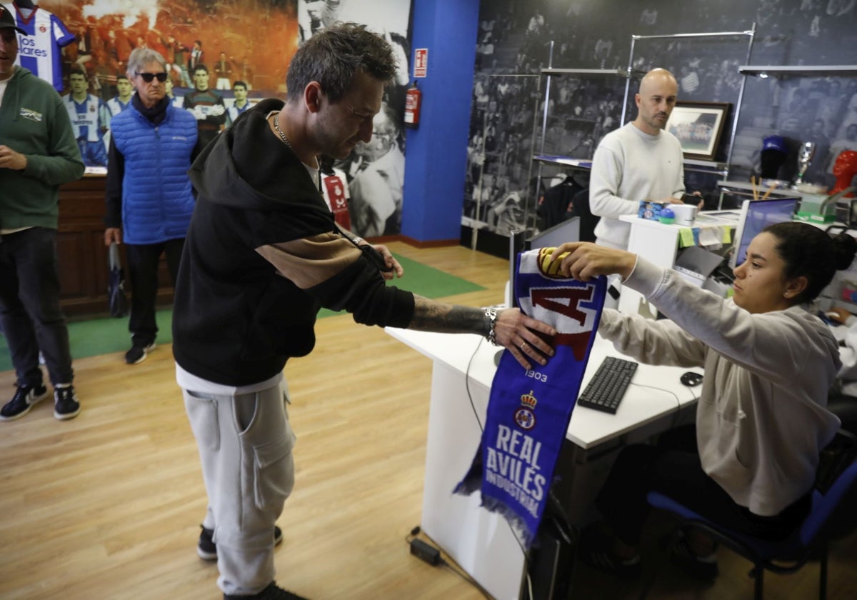 Un aficionado recibe una bufanda de regalo al sacar su entrada en la tienda del club.