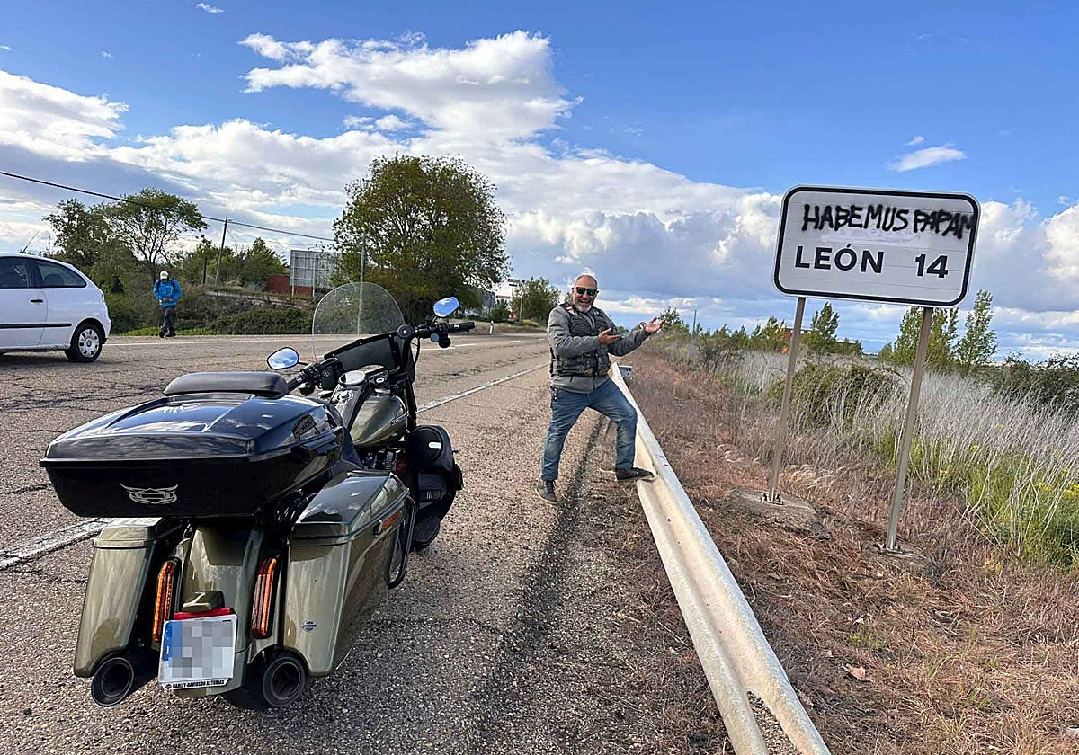 Un motero gijonés muestra el cartel de tráfico leonés 'dedicado' al nuevo Papa.