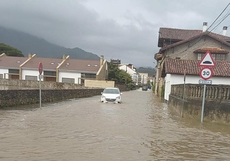 Un vehículo, en plena crecida del río Libardón en Colunga.