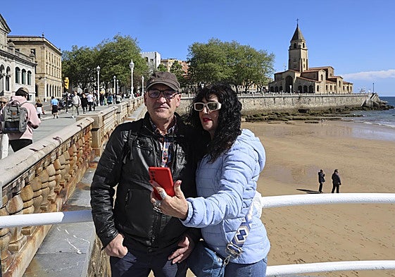 Una pareja se hace una foto en el Muro de San Lorenzo con la iglesia de San Pedro de fondo.