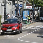 Un joven, por la acera en uno de los patinetes del servicio de alquiler.