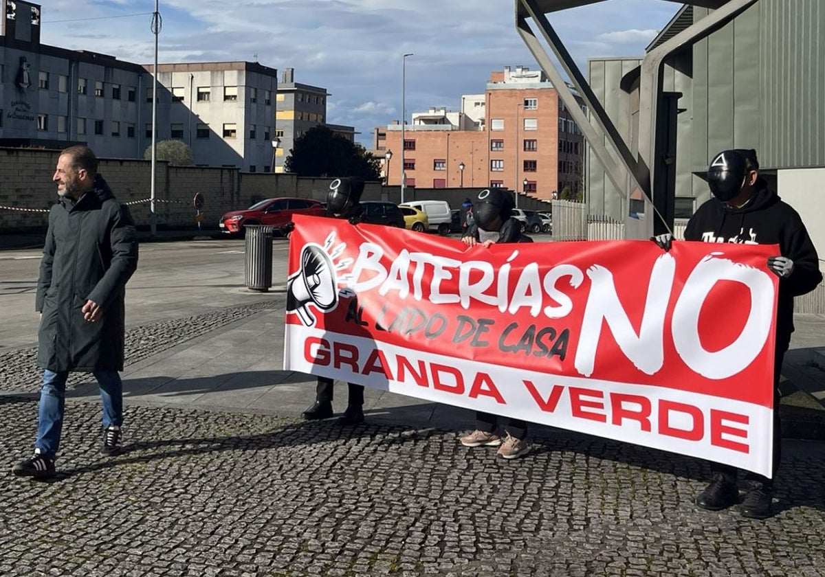 El alcalde de Siero, Ángel García, camina ante una pancarta de protesta vecinal.