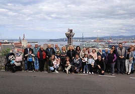 Los vecinos de El Muselín reunidos frente a la sede vecinal del barrio, en el fondo de la foto, el puerto de El Musel.