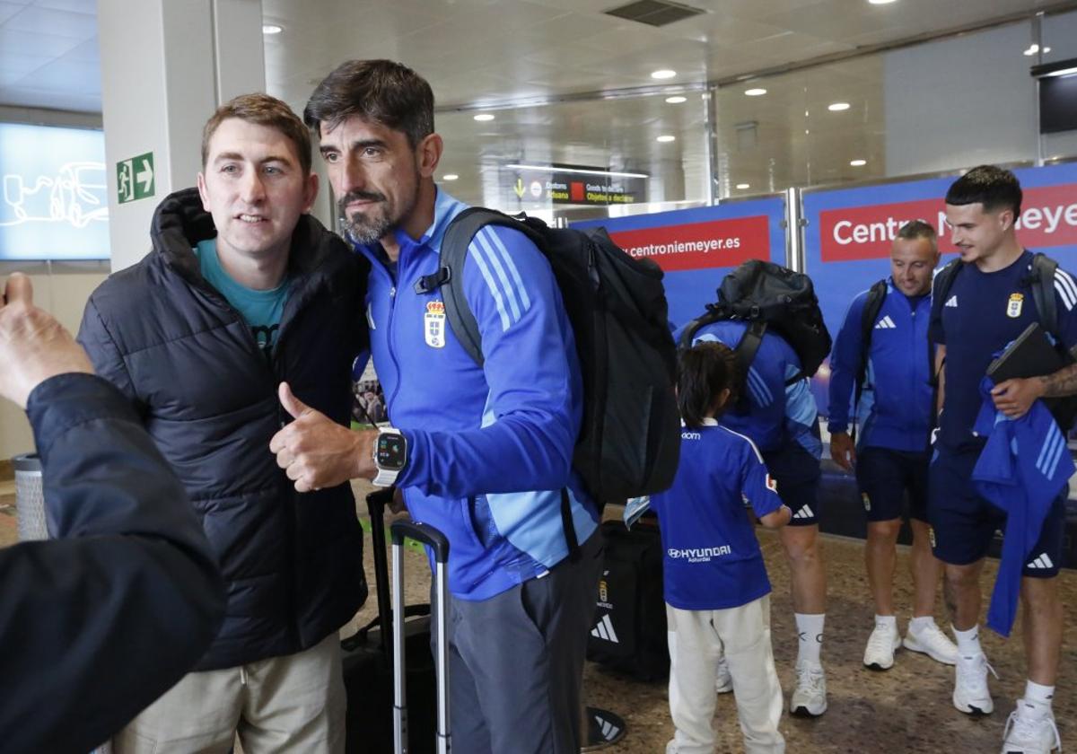 El técnico del Real Oviedo se fotografía, con el pulgar en alto, junto a un seguidor en el Aeropuerto de Asturias.