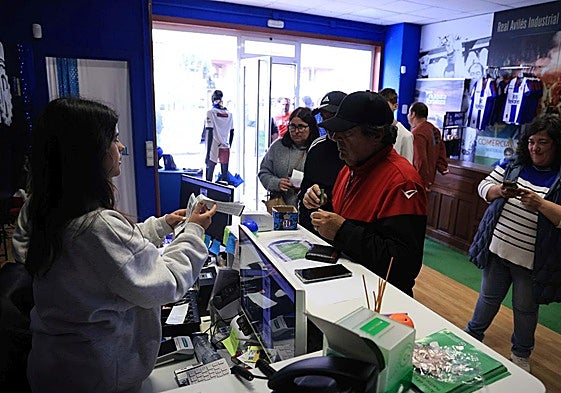 Aficionados del Real Avilés retirando entradas para el partido en la tienda.