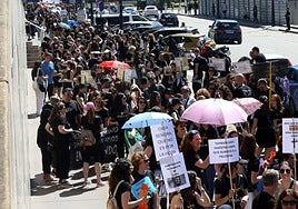 Cientos de docentes esperan para acceder al Registro, protegiéndose del sol con paraguas.