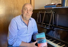 El escritor con el libro en su domicilio de Oviedo, donde reside.