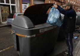 Un hombre deposita una bolsa de basura en un contenedor para residuos orgánicos en Gijón.