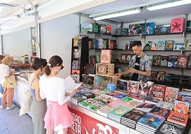 Dos jóvenes ojean algunos de los libros de la feria.