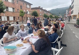 Vecinos disfrutando de la comida en la calle organizada por Festejos de Blimea