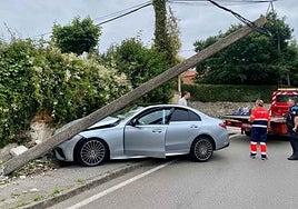 El coche accidentado con el poste del tendido eléctrico caido.