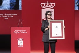 La coordinadora de la red de casas de acogida del Principado, Yoanna Magdalena Benavente, muestra al público la medalla y el diploma de la Casa Malva.