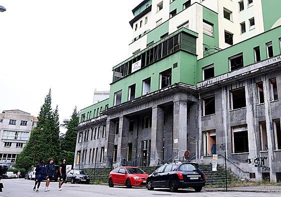 Varios jóvenes pasan por delante del edificio del antiguo Hospital General, donde se han suspendido temporalmente los trabajos.