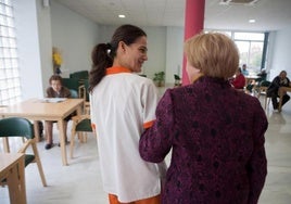 Una profesional camina con una usuaria de un centro especializado en geriatría.