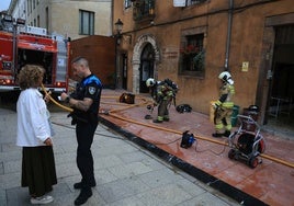 Un agente de la Policía Local se entrevista con una mujer mientras los bomberos trabajaban en el lugar del incendio el lunes.