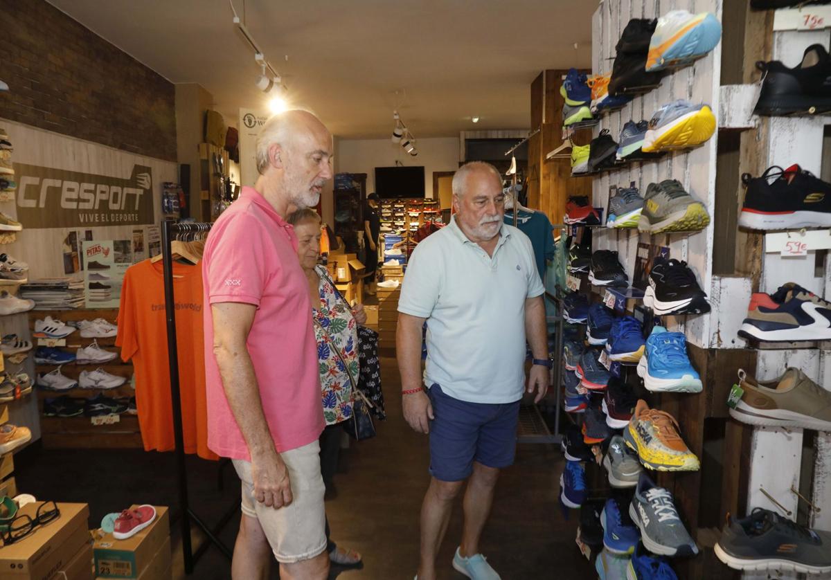 Imagen principal - Arriba, Andrés Crespo, de Cresport, atiende a unos clientes. A la izquierda, Manuel Palizas, encargado de Del Río Uribe Avilés, dobla una camisa de caballero y a la derecha, Anisoara Lenuta Tarcaet, de T&T, coloca una percha.