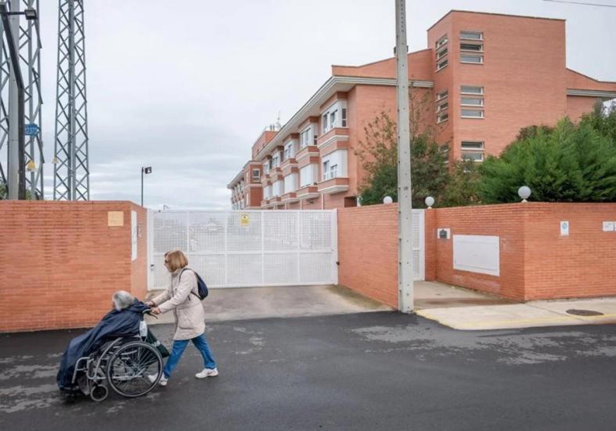 Una mujer pasea a una anciana sentada en su silla de ruedas.