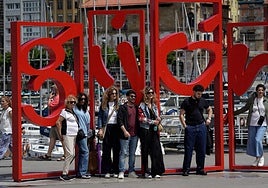 Un grupo de turistas se inmortaliza antes las 'Letronas' de Gijón.