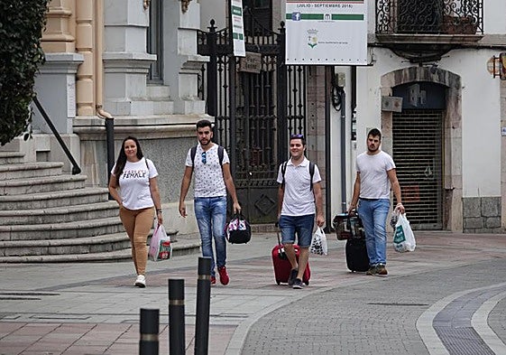 Un grupo de viajeros caminan con sus maletas por Llanes.