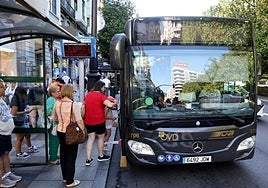 Varios viajeros montan un autobús urbana en una de las paradas de la calle Uría.