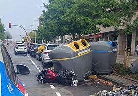 Moto tirada en el suelo en la gijonesa calle Velázquez con los contenedores atrastrados en su caída.