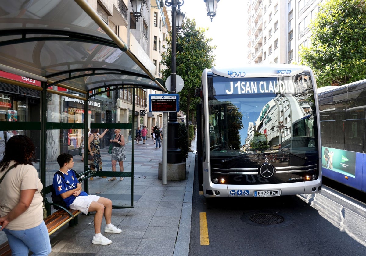 Varias personas esperan el autobús en Oviedo.