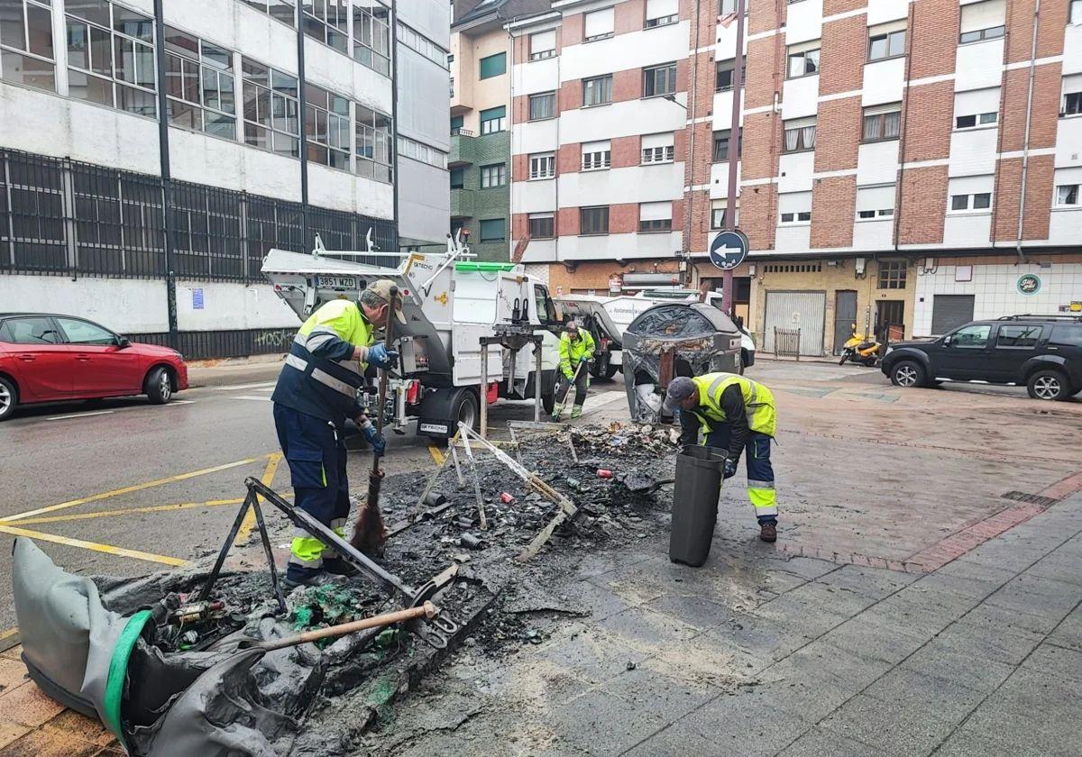 Operarios recogen los restos de los contenedores quemados en la calle la Justicia, en La Felguera, el pasado mes de mayo.